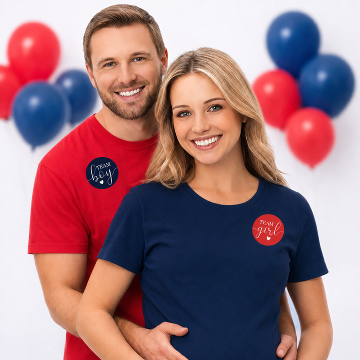 A smiling couple poses in matching custom t-shirts. The man wears a red t-shirt with a circular navy logo that reads 'team hey', and the woman wears a navy t-shirt with a matching circular red logo that reads 'team girl'.