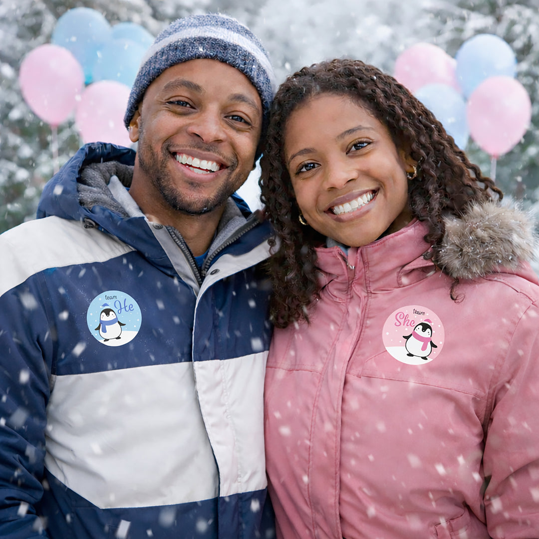 Smiling couple in winter jackets with penguin stickers.